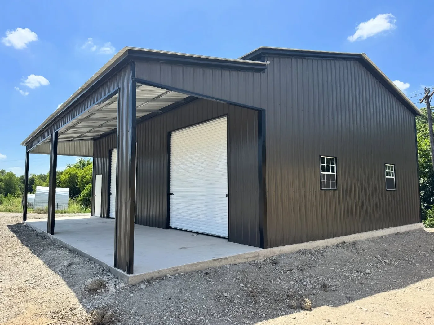 Completed dark-metal building with covered side bay