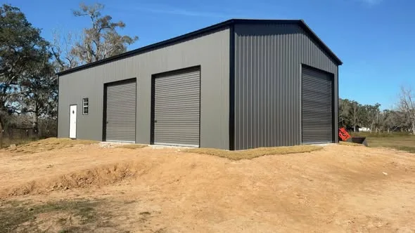 Dark metal building with three closed roll-up doors